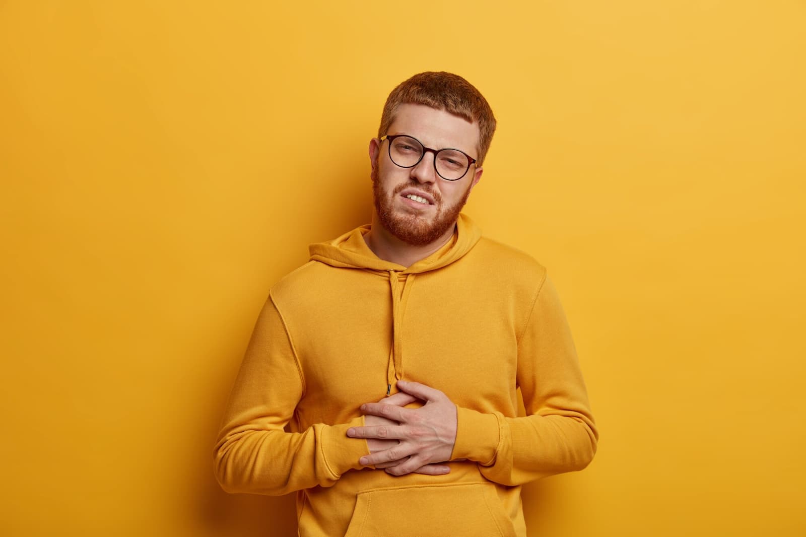 Man holding his stomach on yellow background