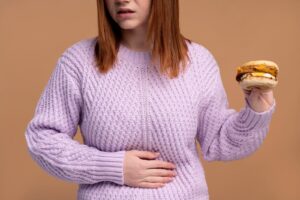 Woman holding her stomach and holding a hamburger