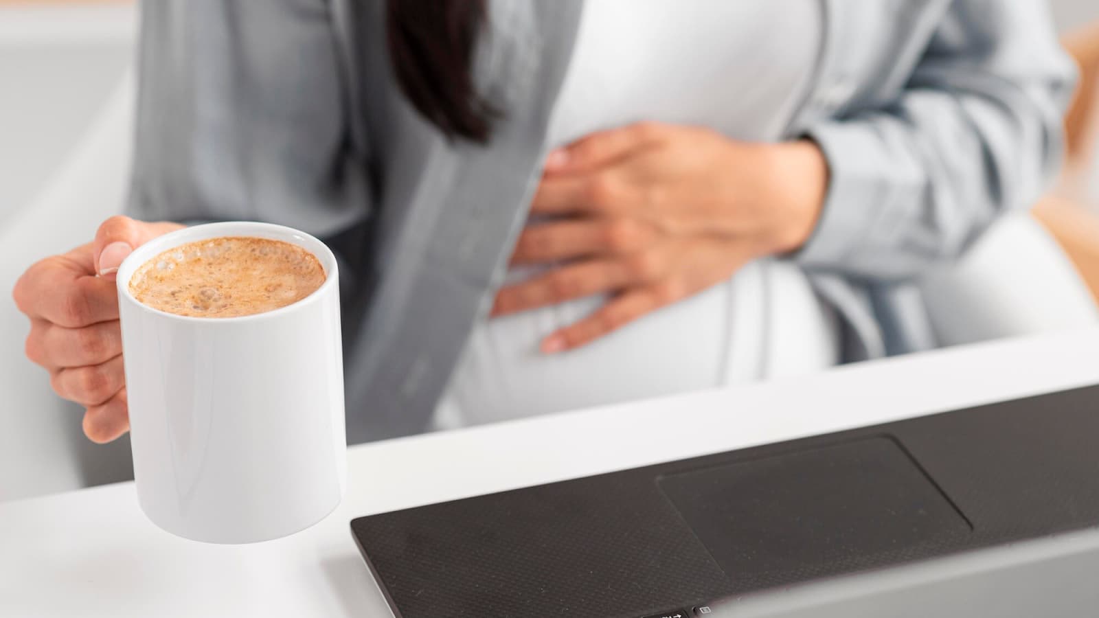 Woman holding a cup of coffee and holding her stomach