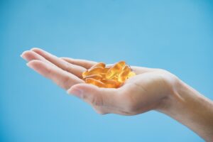 Hand holding pills on blue background